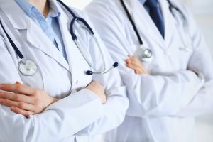 Team of unknown doctors standing straight with arms crossed in hospital. Physicians ready to help. Healthcare, insurance and medicine concept / blog - gynecologists and urologists